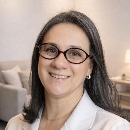 Retrato da fonoaudióloga Marta Andrade, de jaleco branco, na sala de atendimento da clínica.